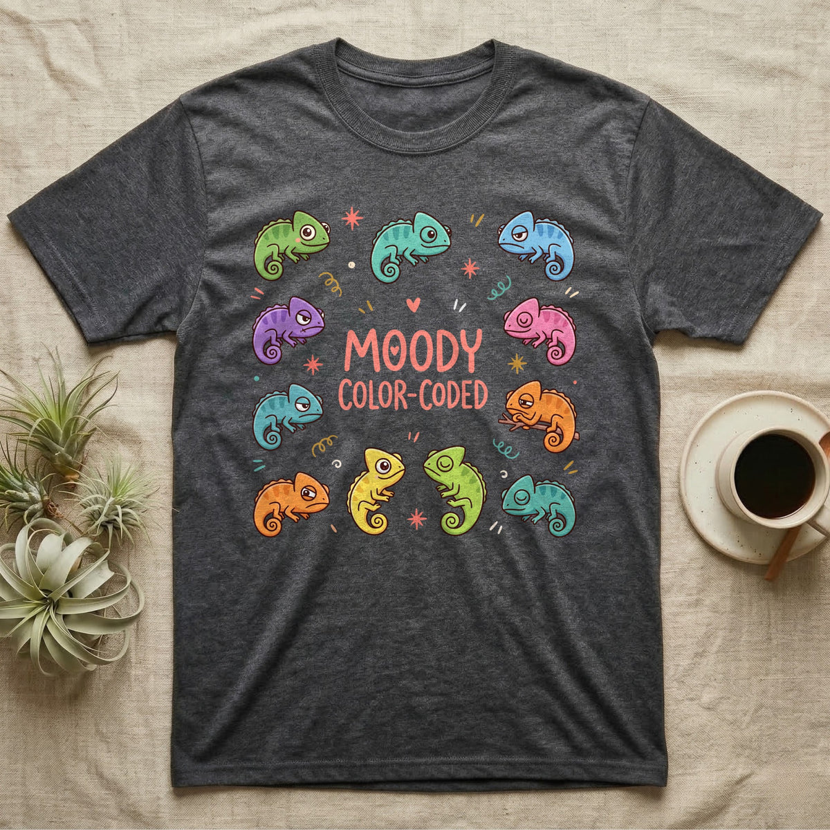 Chameleon Moody T-Shirt in Dark Heather — Ten cartoon chameleons in different colours and moods around the coral-pink words MOODY COLOR-CODED