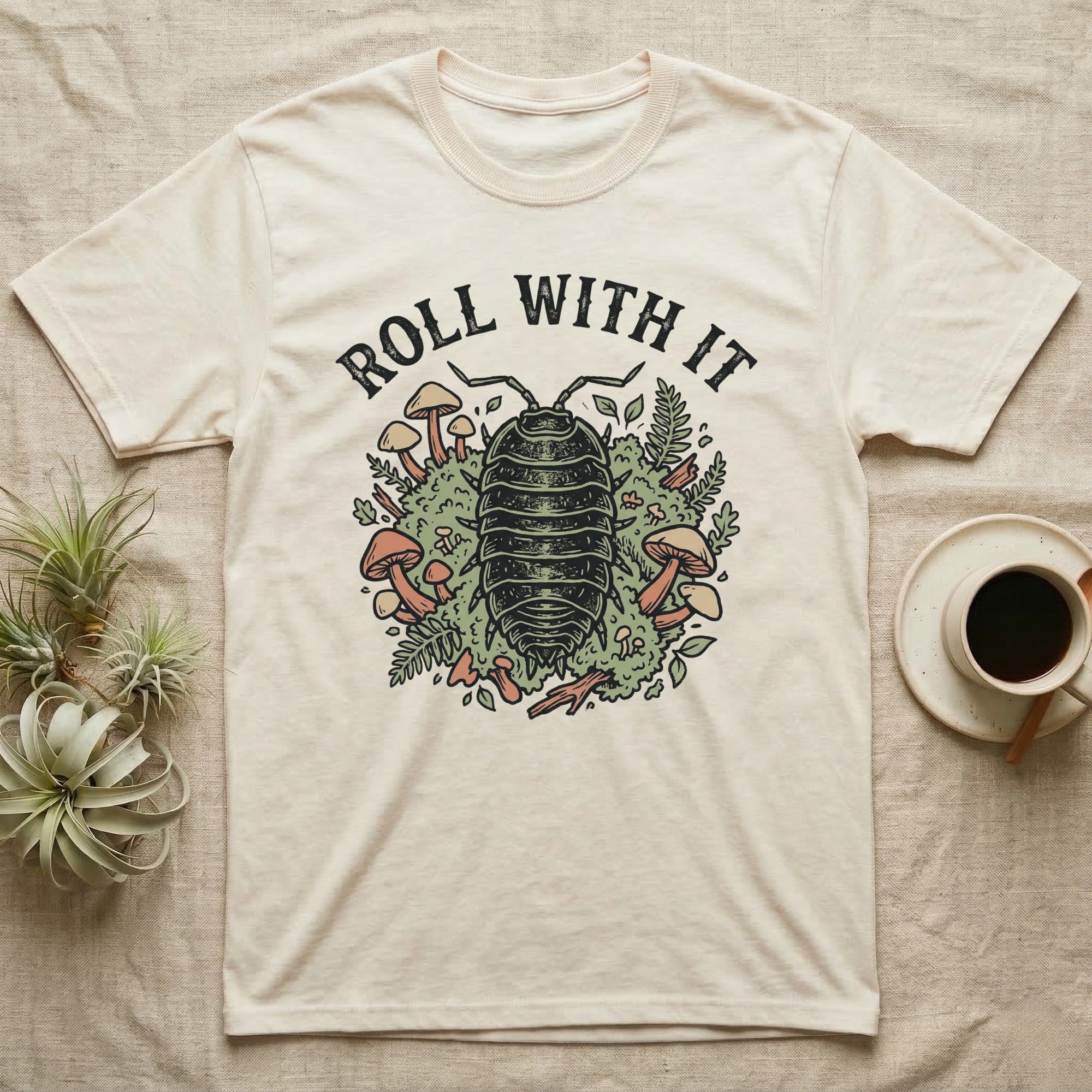 Cream t-shirt with "Roll With It" text above an illustration of a pill bug and mushrooms.