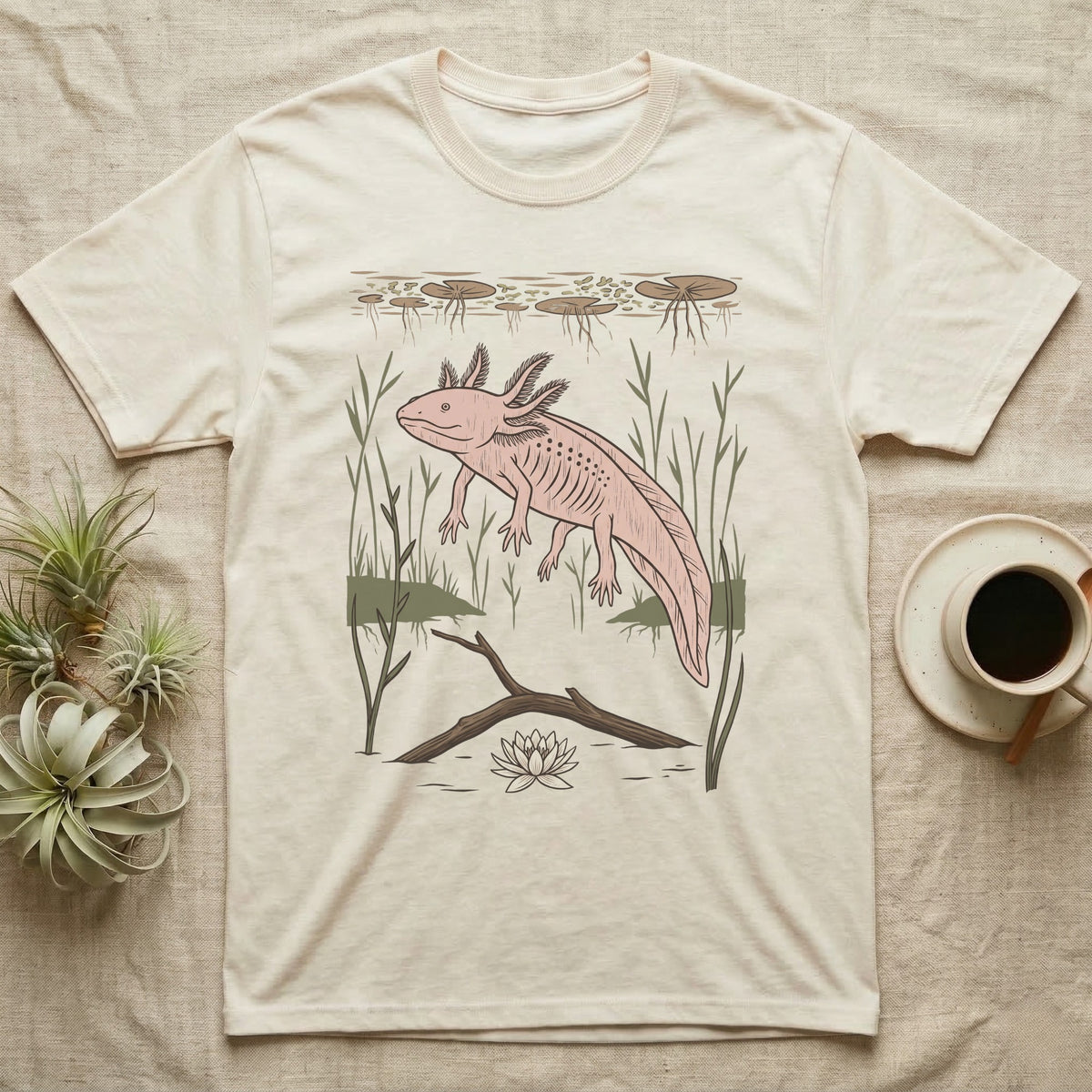Axolotl Home Range T-Shirt in Natural — Woodcut-style illustration of an axolotl drifting among reeds and lily pads in a Xochimilco canal, no on-shirt text.