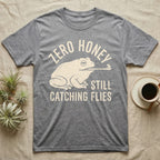 Tree Frog Proverb T-Shirt in Sport Grey — Worn cream print of a dumpy White's tree frog catching a fly with its tongue under the words Zero Honey, Still Catching Flies