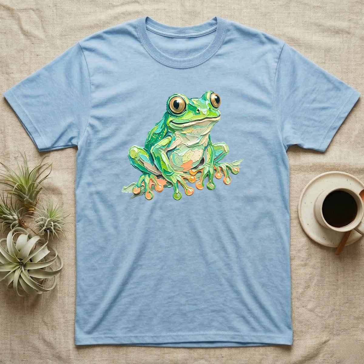 Light blue t-shirt with a vibrant green frog illustration on the front.