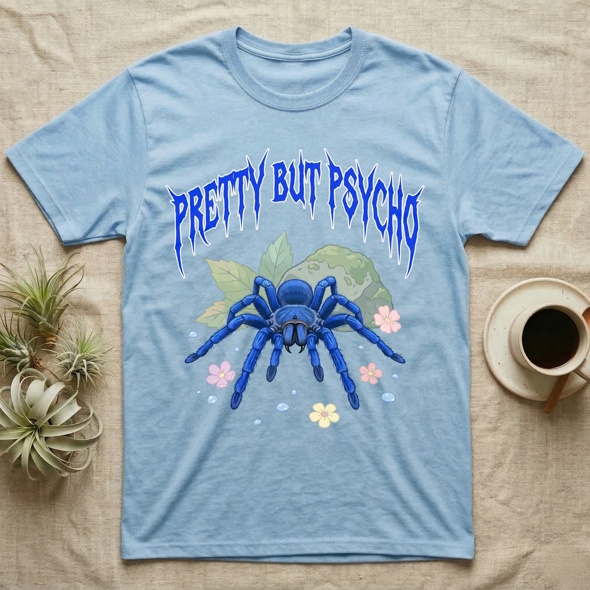 Cobalt Blue Tarantula Feral T-Shirt in Light Blue — Cobalt blue tarantula with electric-blue legs under jagged cobalt metal text PRETTY BUT PSYCHO with pastel blossoms