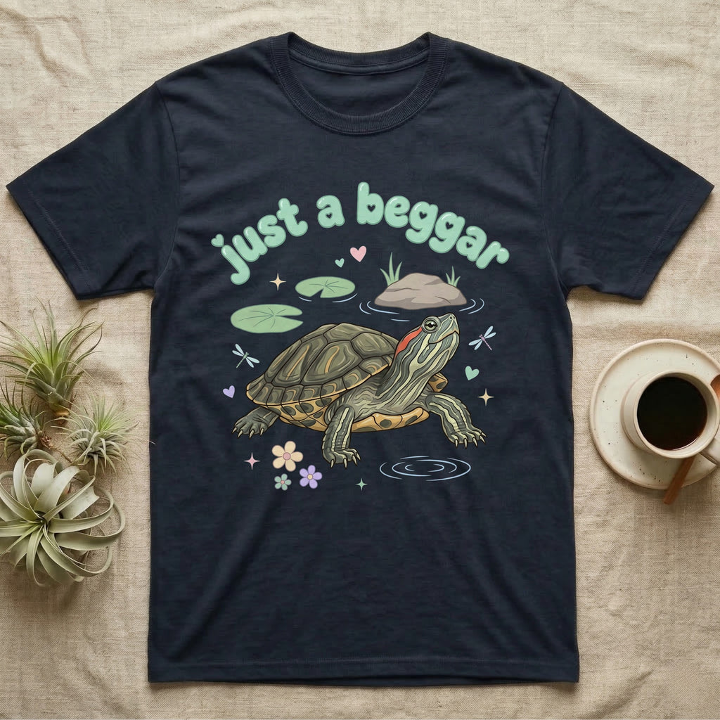 Red-Eared Slider Softie T-Shirt in Navy — Red-eared slider turtle stretching its neck to beg, under pastel bubble text "just a beggar" with hearts.