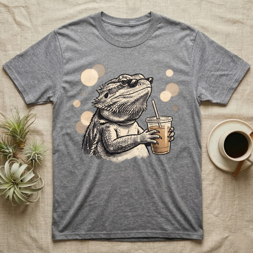 Cold Brew Bearded Dragon T-Shirt in Sport Grey — Flat near-photoreal illustration of a bearded dragon in tiny sunglasses holding a cold brew with warm bokeh.