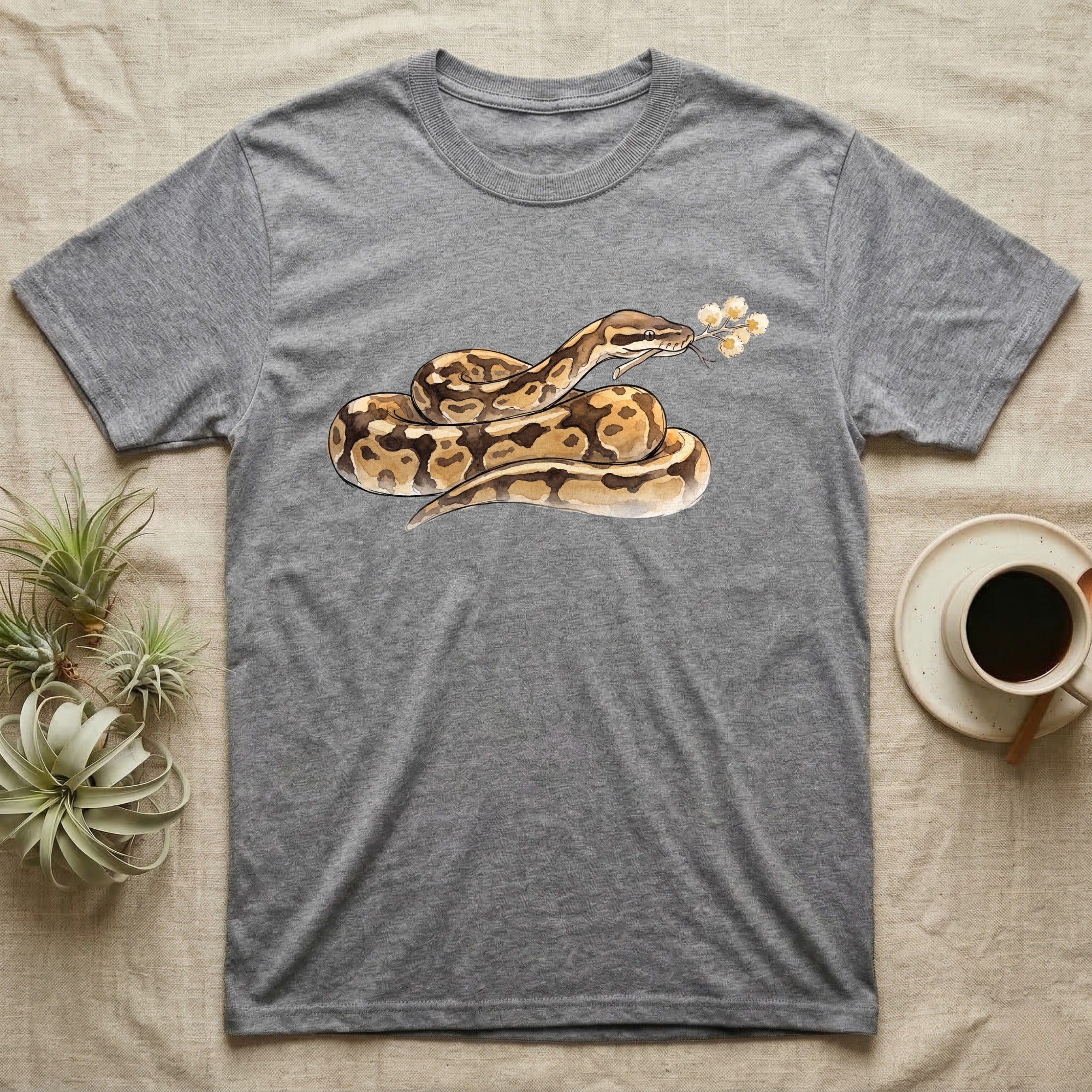Ball Python Blossom T-Shirt in Sport Grey — Watercolor illustration of a tan-and-brown ball python holding an acacia blossom sprig, on a dark grey t-shirt.