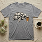 Slow Drip Tortoise T-Shirt in Sport Grey — Flat meme-style illustration of a sulcata tortoise reaching slowly toward a tall iced slow-drip coffee.