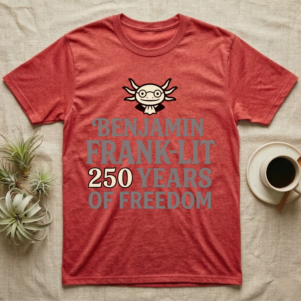 Axolotl Benjamin Franklin T-Shirt in Heather Red — Flat cream axolotl as Ben Franklin in glasses above bold text reading Benjamin Frank-Lit, 250 Years of Freedom.