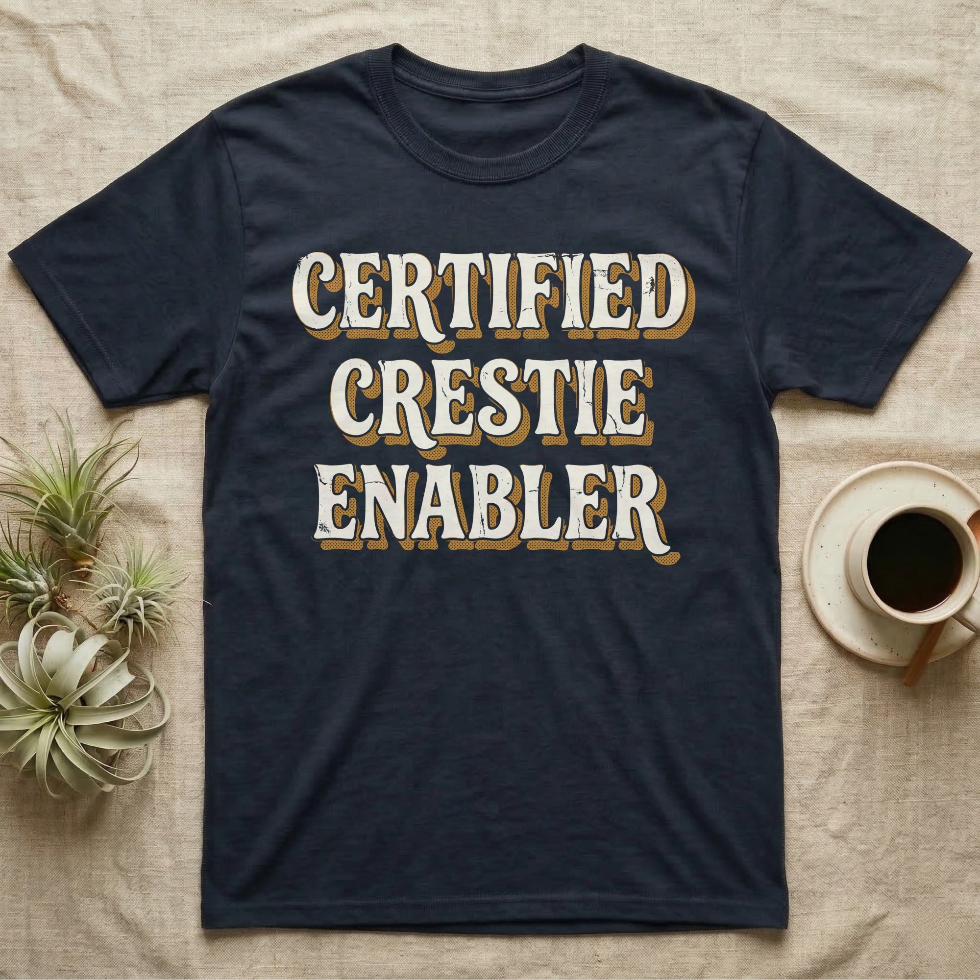 Certified Crestie Enabler T-Shirt in Navy — Bold retro drop-shadow wordmark reading "Certified Crestie Enabler" in cream and ochre on a grey background.