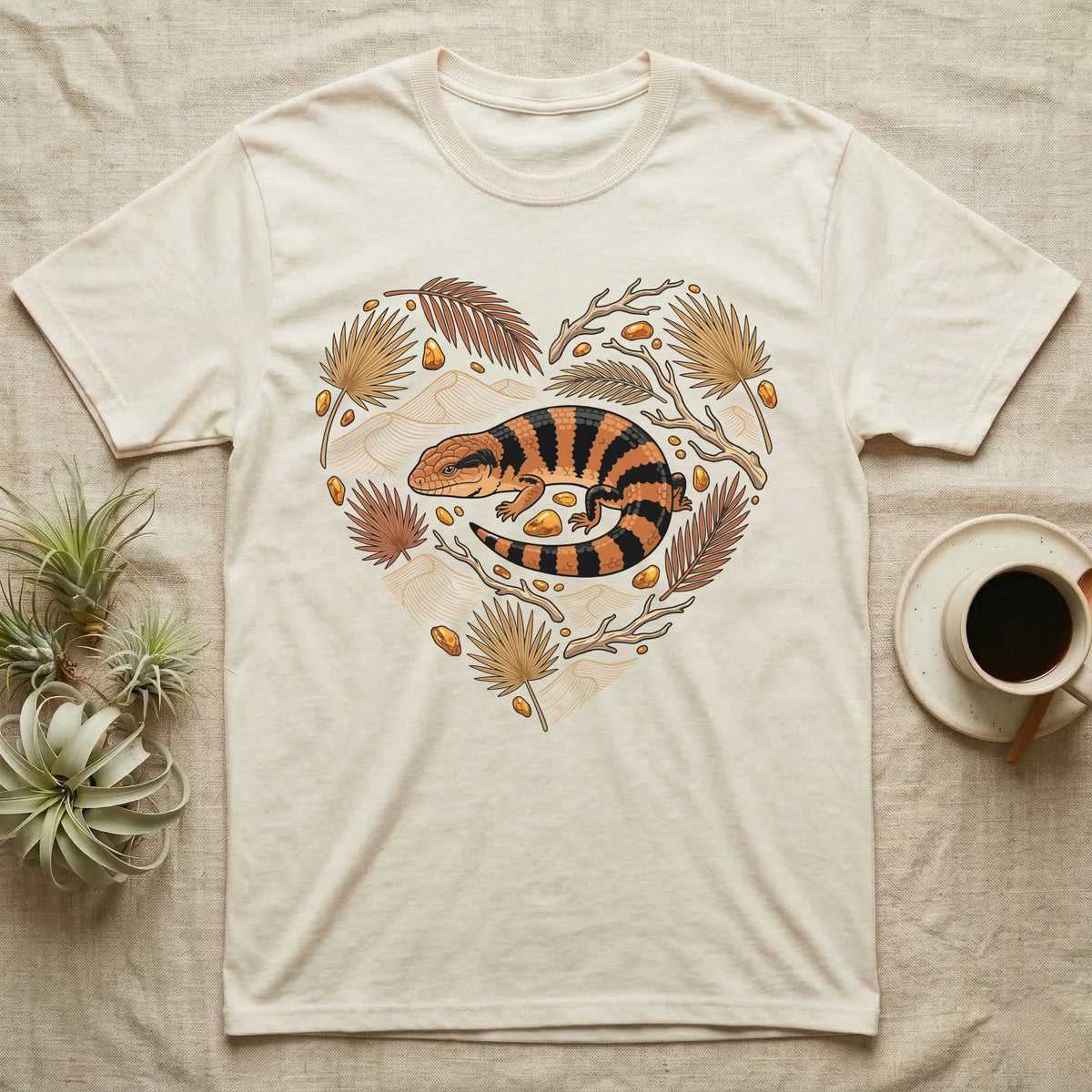 Cream t-shirt with a heart-shaped design of a lizard and botanical elements.