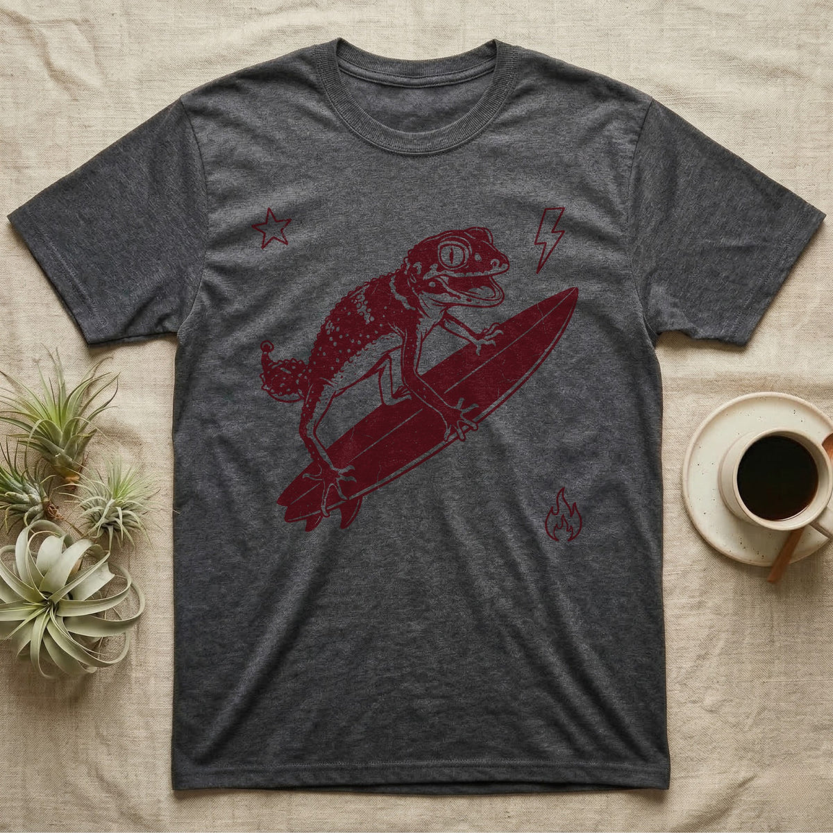 Knob-Tailed Gecko Surfing T-Shirt in Dark Heather — Distressed one-ink illustration of a knob-tailed gecko riding a surfboard, airborne at the peak of an aerial.