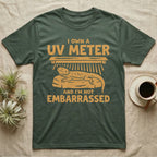 Reptile Keeper UV Meter T-Shirt in Military Green — Linocut block-print badge of a UVB tube lamp above an empty basking rock, ringed by carved slogan lettering.
