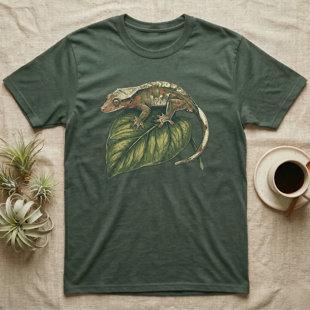 Green t-shirt with crested gecko on large green leaf illustration.
