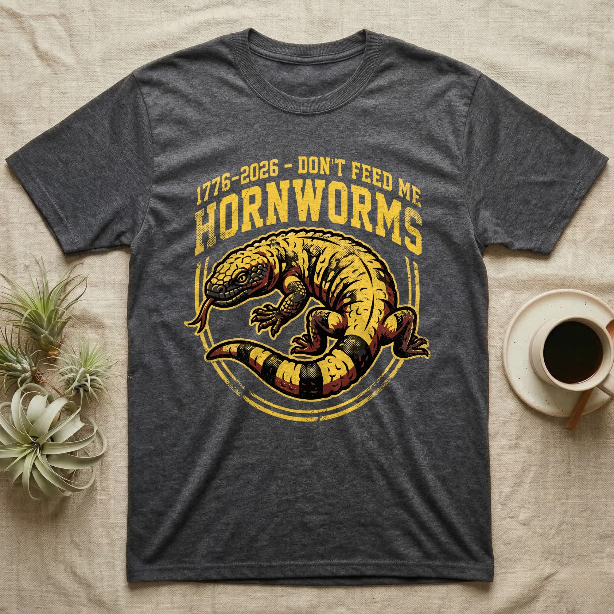 Gila Monster Hornworms Tee in Dark Heather — Bold gold and maroon woodcut tee of a Gila monster with banded tail, large text reading Don't Feed Me Hornworms, on black.