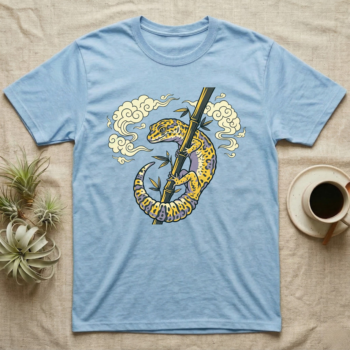 Light blue t-shirt with a yellow gecko on a bamboo stalk illustration.