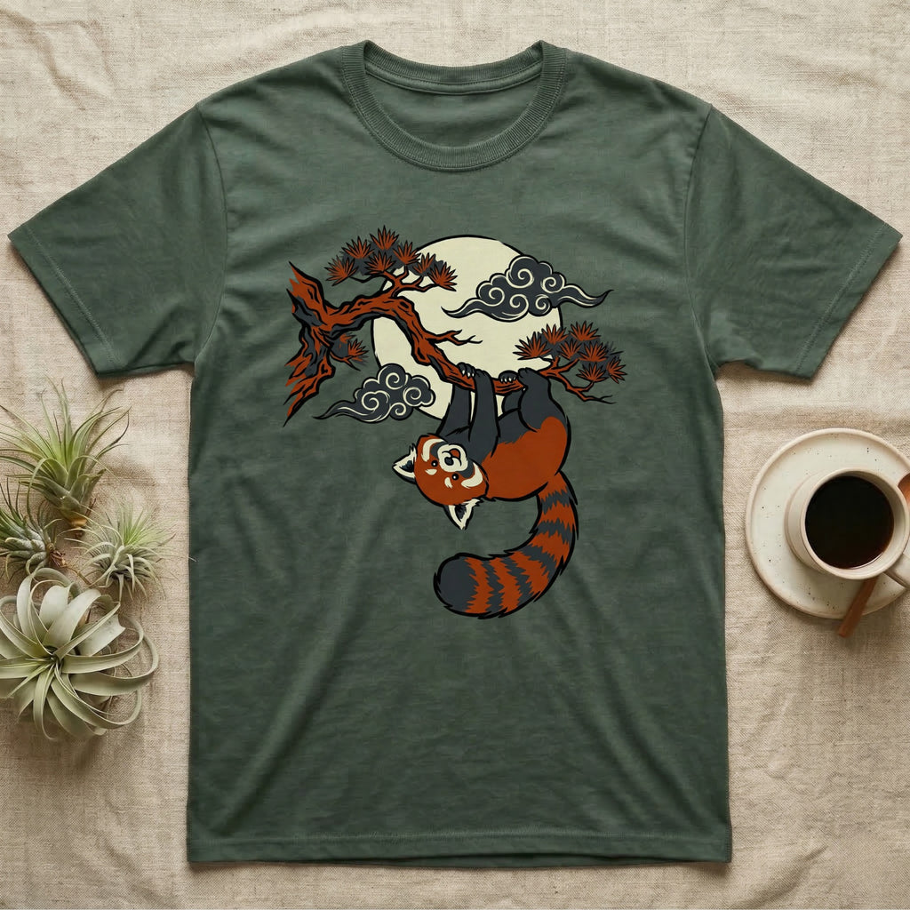 Green t-shirt with a red panda hanging from a tree branch under a moon.