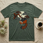 Green t-shirt with a red panda hanging from a tree branch under a moon.