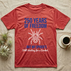 Tarantula Waiting For Cricket Tee in Heather Red — Minimalist geometric tee with a low-poly white tarantula and blue text reading 250 Years Of Freedom but my spider's still waiting for a cricket.