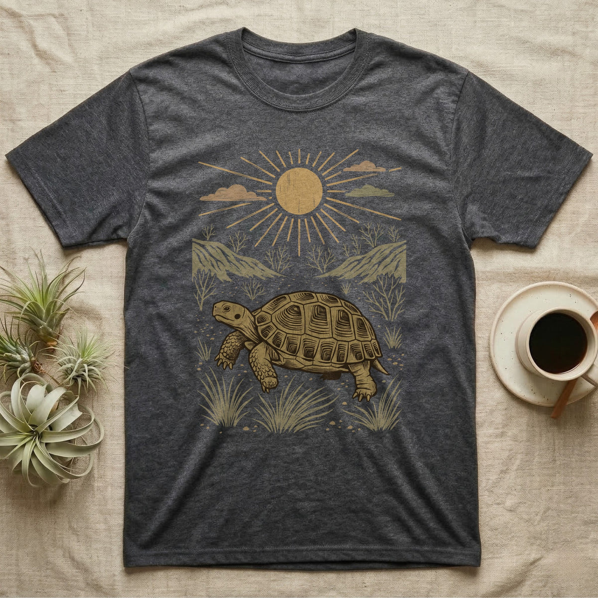 Russian Tortoise Home Range T-Shirt in Dark Heather — Woodcut-style illustration of a Russian tortoise walking across gravelly steppe under a full sun with dry hills behind, no on-shirt text.