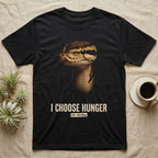 Photographic mugshot of a ball python staring down the lens above the distressed hook I Choose Hunger, on strike. — shown on a Black tee.