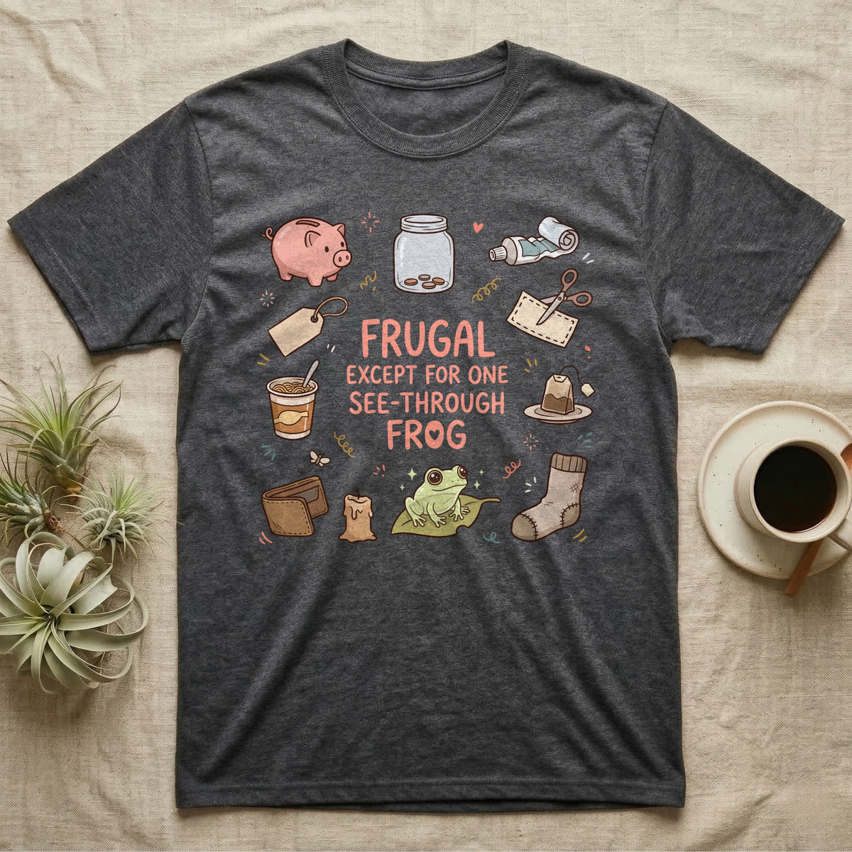 Glass Frog Frugal T-Shirt in Dark Heather — Cartoon glass frog on a leaf under the words Frugal except for one see-through frog, ringed by a piggy bank, coin jar, coupons and other thrifty things