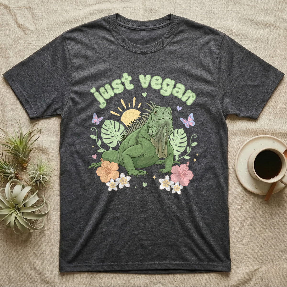 Green Iguana Baby T-Shirt in Dark Heather — Green iguana with spiky crest and dewlap among pastel leaves and flowers under puffy green bubble text "just vegan".