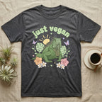 Green Iguana Baby T-Shirt in Dark Heather — Green iguana with spiky crest and dewlap among pastel leaves and flowers under puffy green bubble text "just vegan".