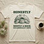 Snapping Turtle Rock T-Shirt in Natural — Engraved snapping turtle hunkered like a mossy rock, facing forward, with the words Honestly, Mostly a Rock, Occasionally I Bite