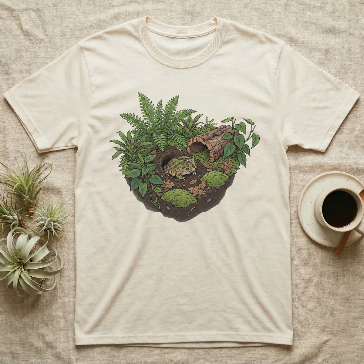 Pacman Frog Vivarium T-Shirt in Natural — Botanical illustration of a pacman frog thriving in a planted bioactive vivarium beside a small empty plastic cup.