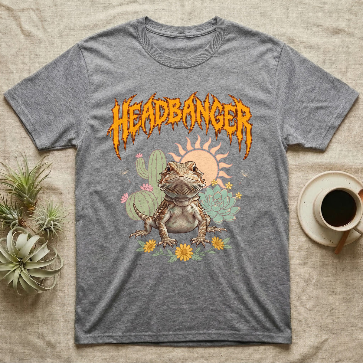 Central Bearded Dragon Feral T-Shirt in Sport Grey — Baby bearded dragon in a pastel desert scene under a spiky amber metal wordmark reading HEADBANGER.