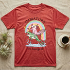 Axolotl Immature T-Shirt in Heather Red — Crayon drawing of a pink axolotl riding a leaping green frog through a rainbow, sparkler lit, under IMMATURE
