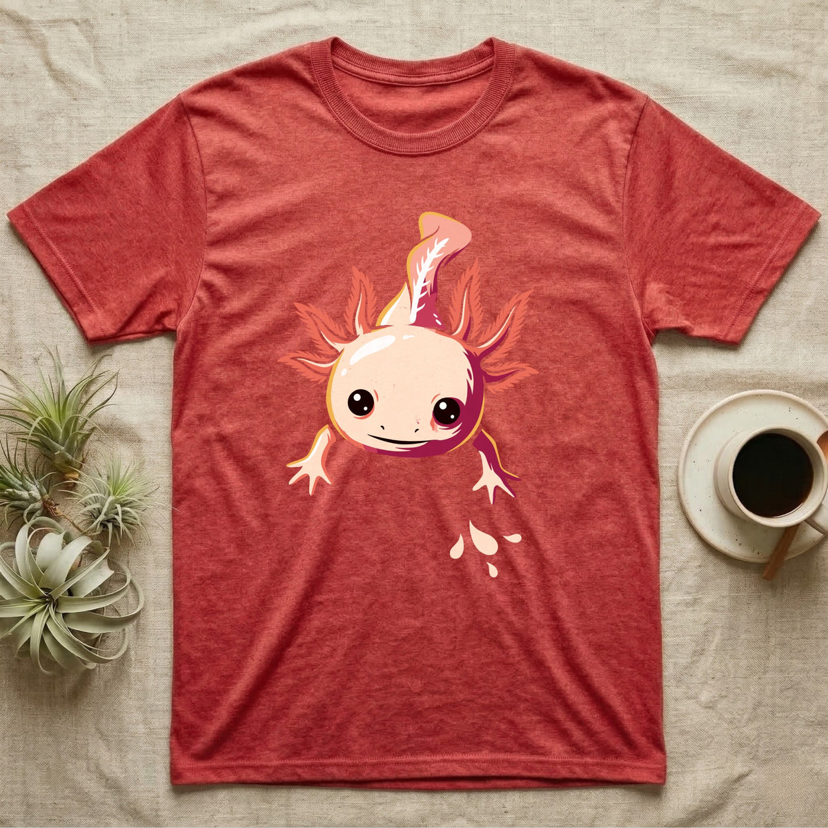 Cute chibi illustration of a smiling cream and coral-pink axolotl floating with splashing water droplets, no on-shirt text. — shown on a Heather Red tee.