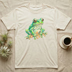 Cream t-shirt with vibrant green frog illustration on a neutral linen background.