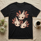Vintage comic screen-print illustration of three axolotls clustered together with coral feathery gills and sparkling star-highlighted eyes, graphic-only, no text. — shown on a Black tee.