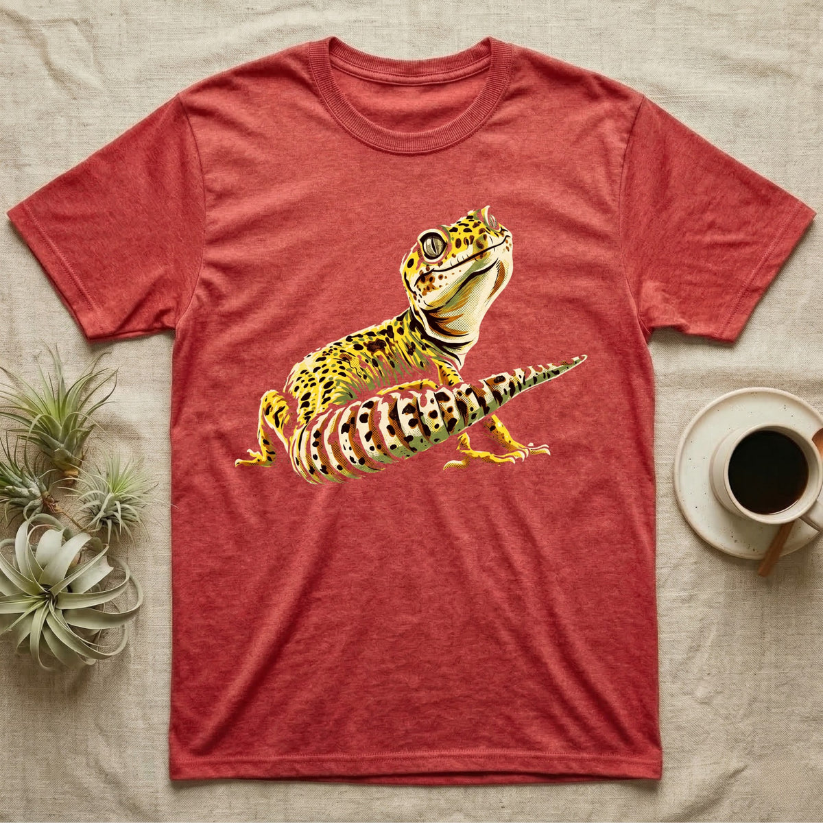 Illustration of a smiling leopard gecko with a plump curled spotted tail, bold vintage-comic ink outlines and halftone shading, graphic-only, no text. — shown on a Heather Red tee.