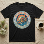 Black t-shirt with "Beach Club Home Is Where I Crawl It" surf-themed circular graphic.
