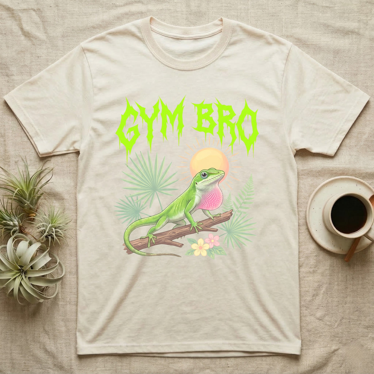 Green Anole Feral T-Shirt in Natural — Green anole mid push-up with flared pink dewlap under a jagged neon-lime metal "GYM BRO" wordmark and pastel ferns.