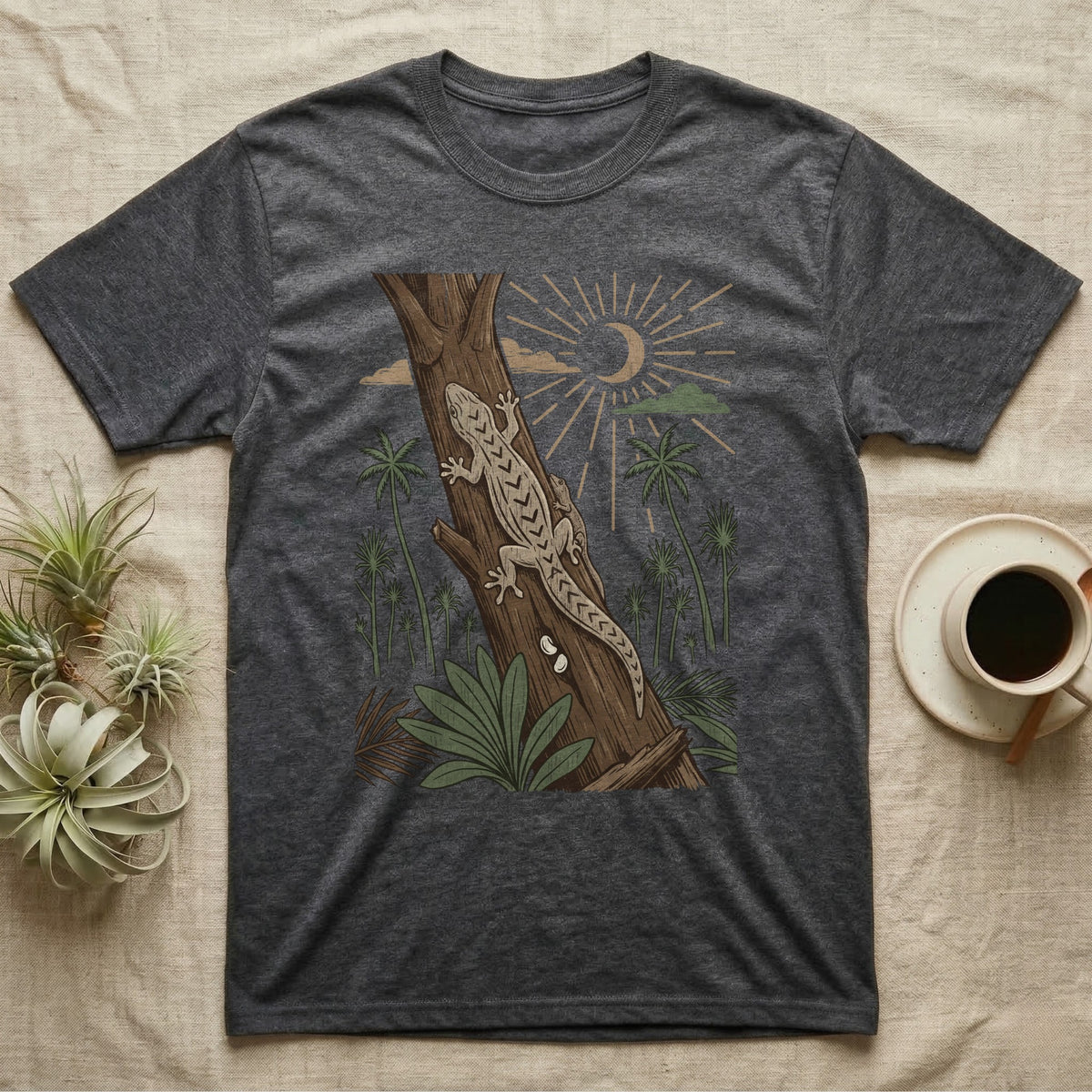Mourning Gecko Home Range T-Shirt in Dark Heather — Woodcut-style illustration of two mourning geckos on a palm trunk with a pair of eggs in the bark and palms behind, no on-shirt text.
