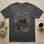 Red-Knee Tarantula Home Range T-Shirt in Dark Heather — Woodcut-style illustration of a Mexican red-knee tarantula at its burrow entrance under a rock slab with desert scrub behind, no on-shirt text.