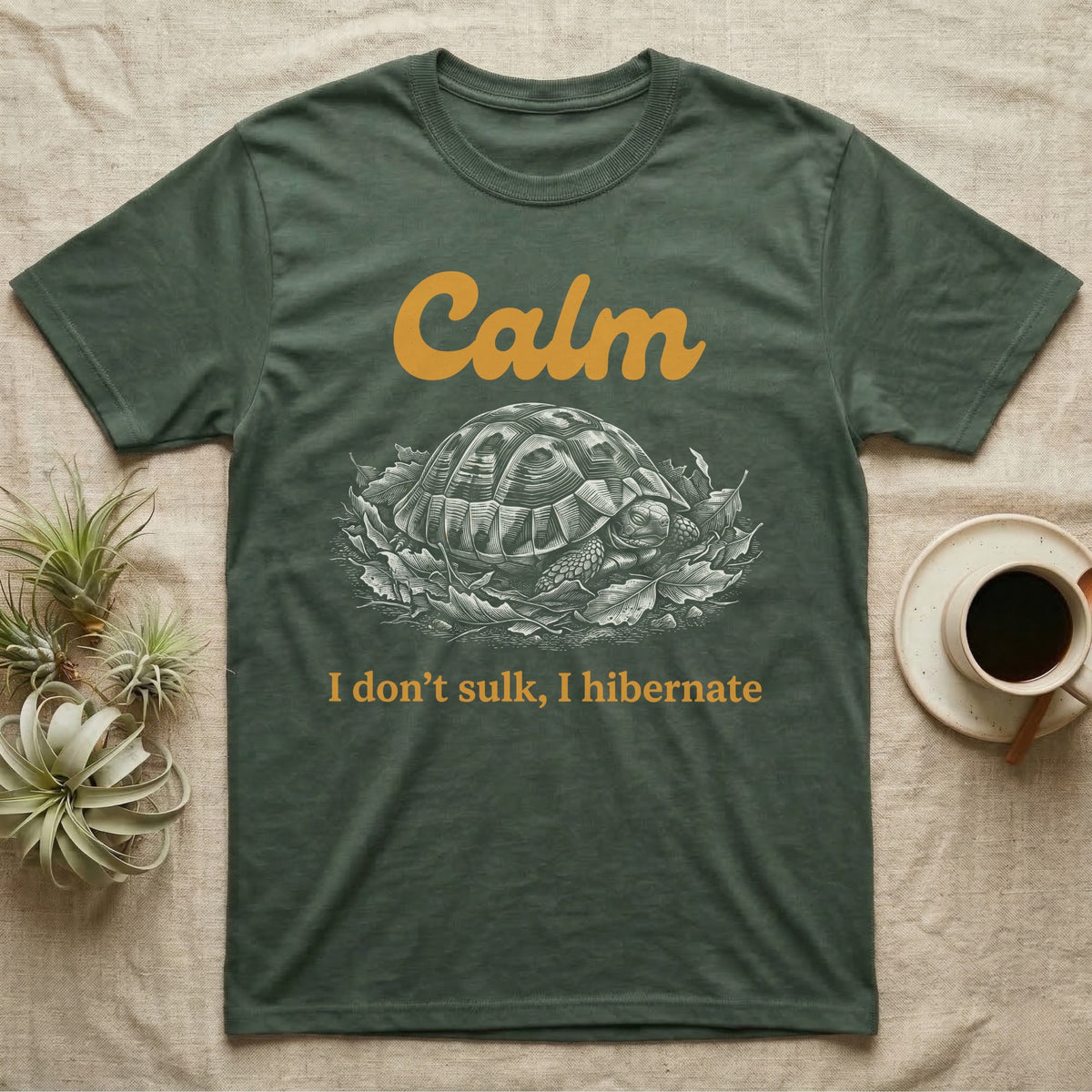 Hermann's Tortoise Calm T-Shirt in Military Green — White-line engraving of a Hermann's tortoise tucked into its shell in dry leaves under the word Calm