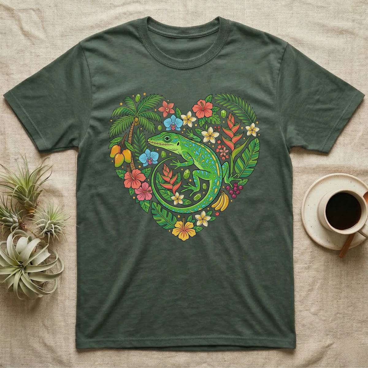 Green lizard surrounded by tropical flowers and fruit in a heart shape on a dark green t-shirt.