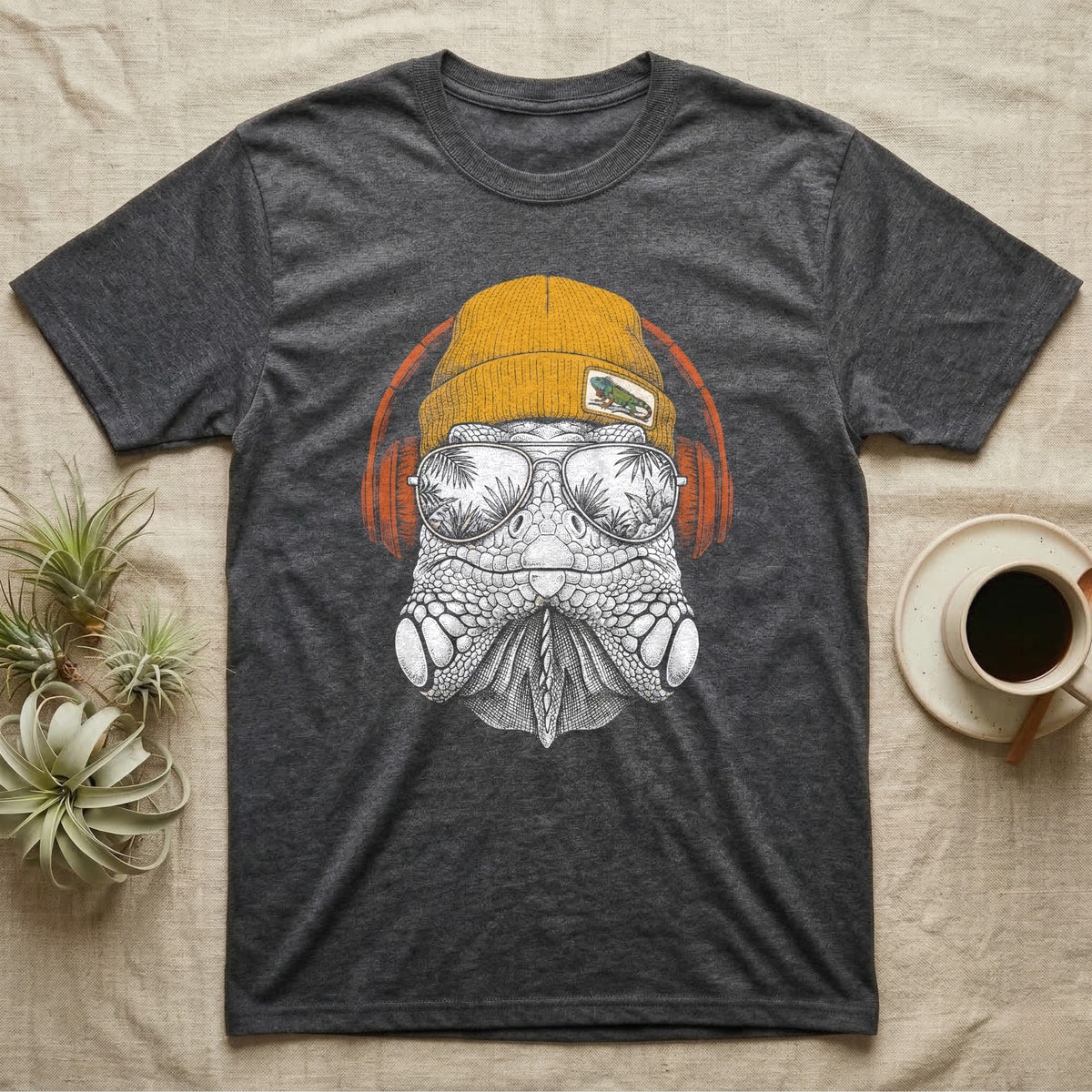 Green Iguana Headphones T-Shirt in Dark Heather — Engraved green iguana with jowls and dorsal spines in a beanie and headphones, aviators reflecting a rainforest.