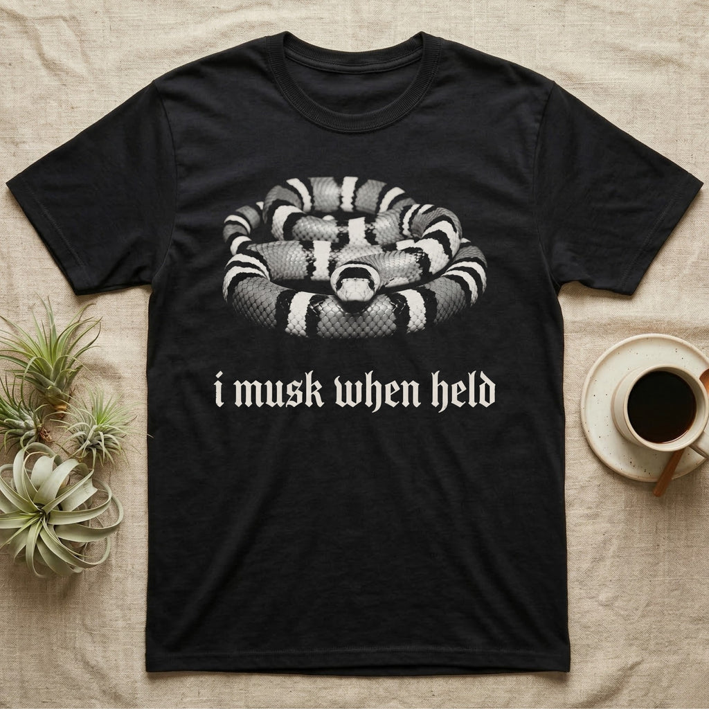 Milk Snake Musk T-Shirt in Black — One-ink photo of a calm milk snake facing forward on its coils, above the blackletter line i musk when held