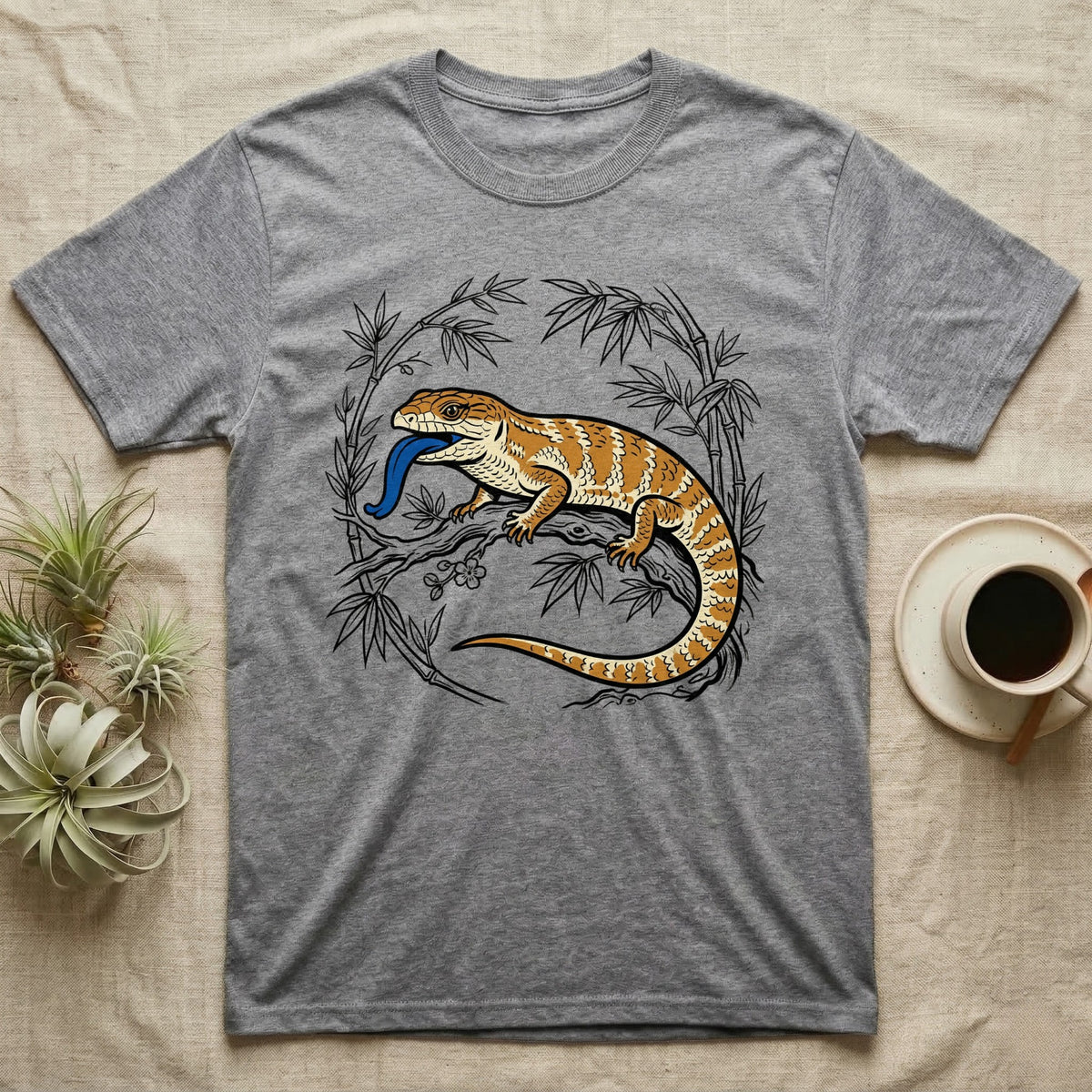 Grey t-shirt with illustrated bearded dragon and blue tongue among bamboo.