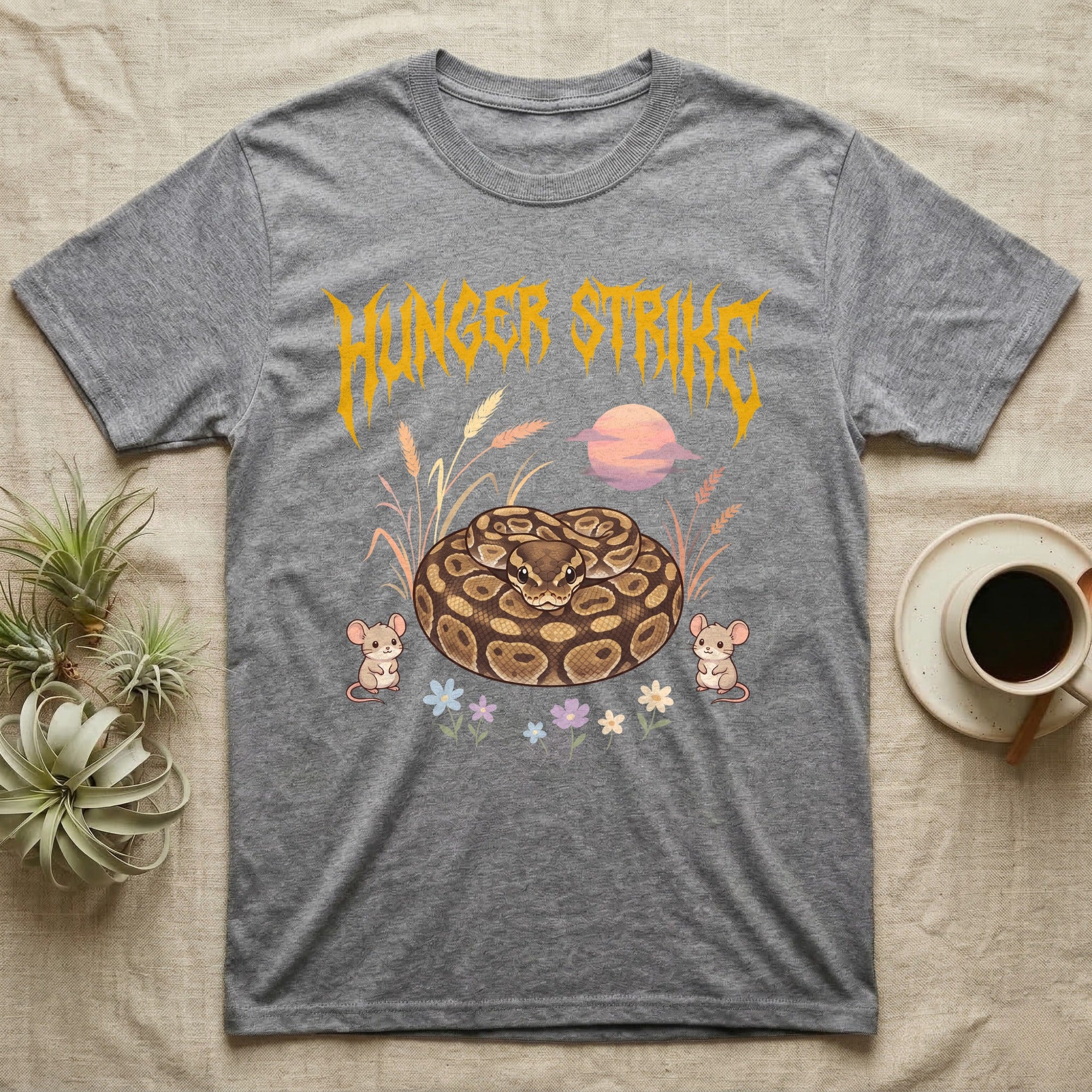 Ball Python Feral T-Shirt in Sport Grey — Ball python coiled in a loaf in a pastel savanna scene under a spiky honey-gold metal wordmark reading HUNGER STRIKE.