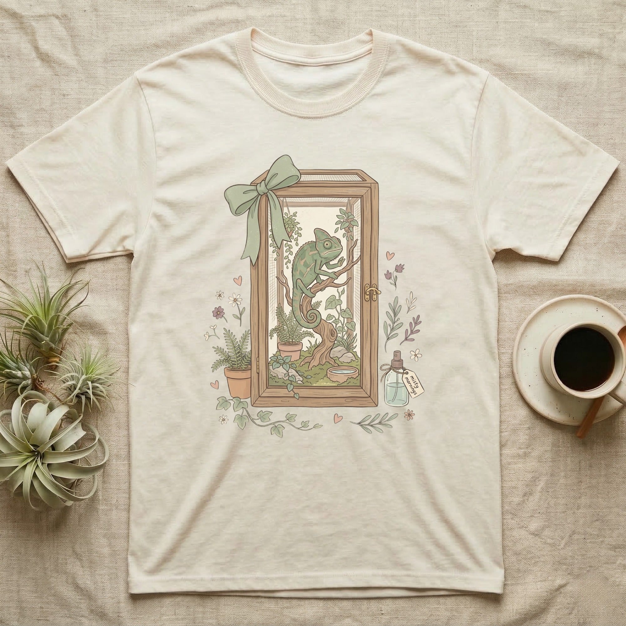 Cream t-shirt with framed illustration of a chameleon in a terrarium.