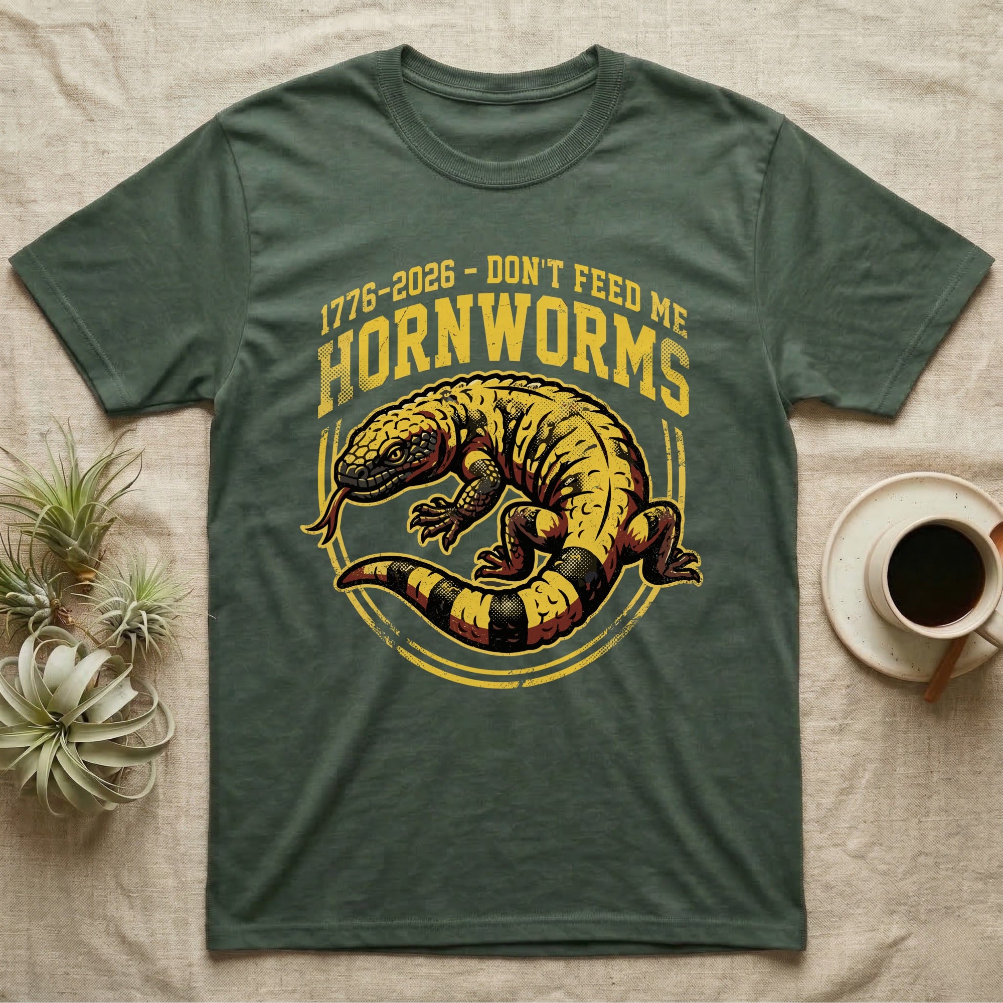Gila Monster Hornworms Tee in Military Green — Bold gold and maroon woodcut tee of a Gila monster with banded tail, large text reading Don't Feed Me Hornworms, on black.