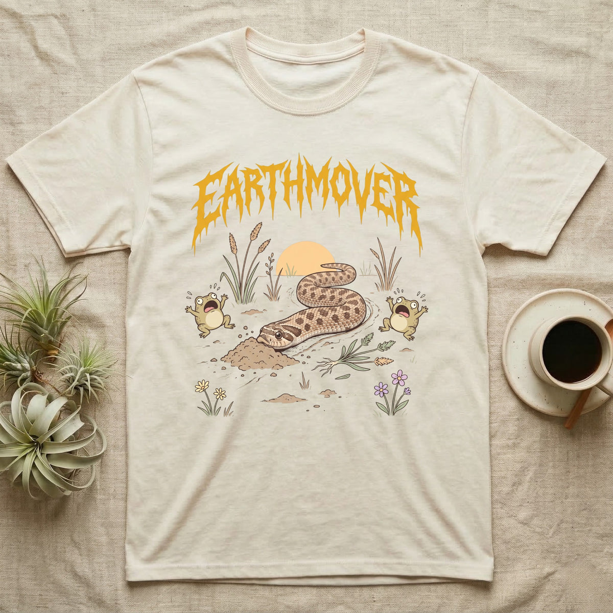 Western Hognose Earthmover T-Shirt in Natural — Western hognose snake bulldozing a mound of dirt as two frogs scream, under dripping EARTHMOVER lettering with a low sun and wildflowers.