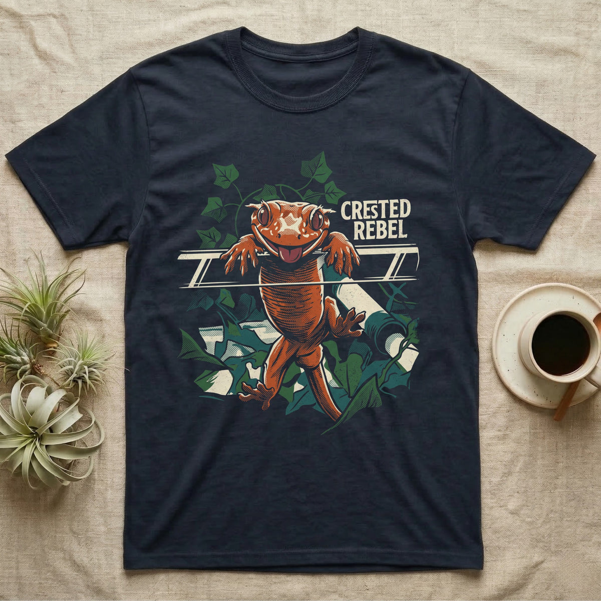 Illustration of a crested gecko hanging tongue-out over a rail among ivy leaves, bold distressed lettering reading Crested Rebel. — shown on a Navy tee.