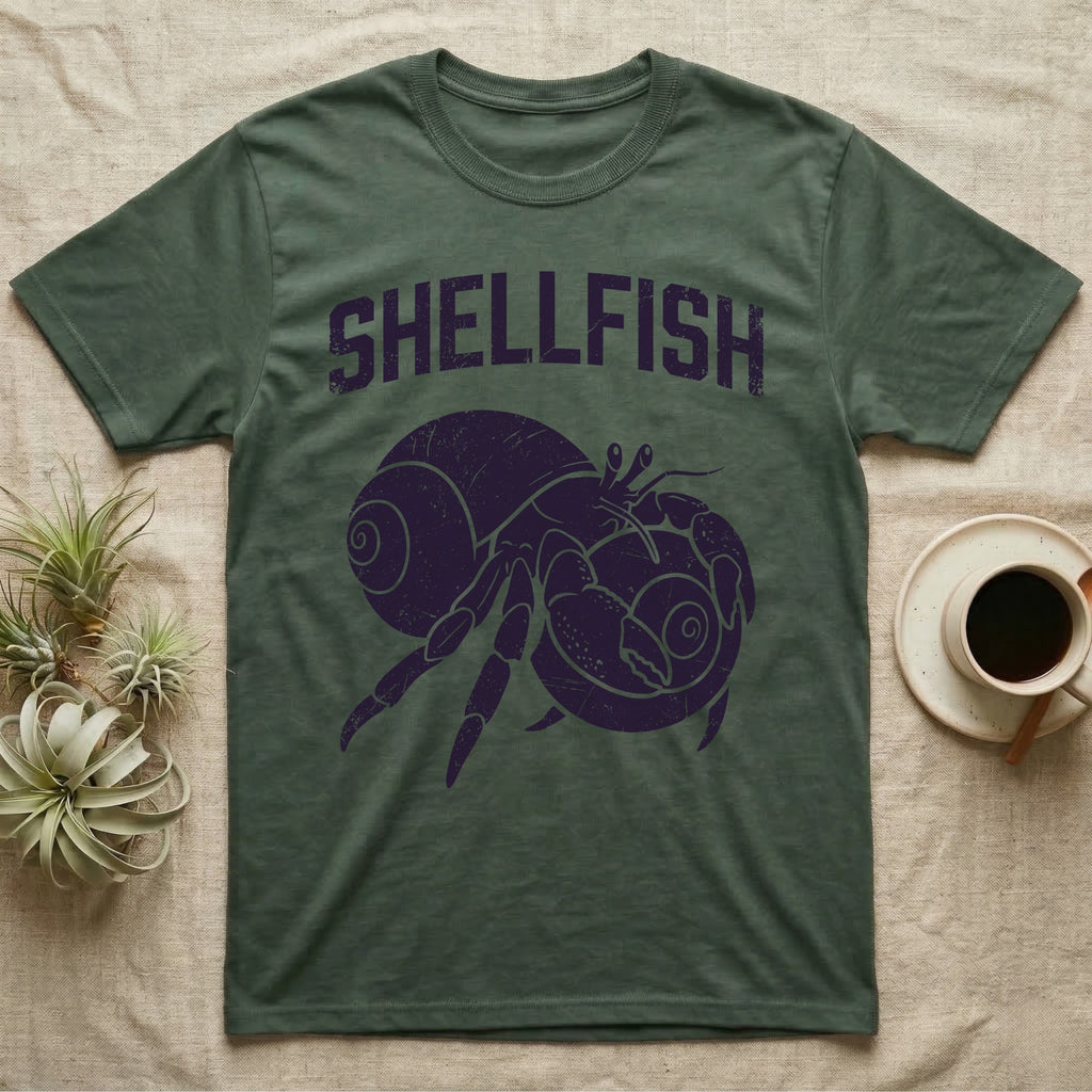 Hermit Crab Shellfish T-Shirt in Military Green — Worn purple one-ink print of a hermit crab hugging a big spare shell to its chest under the word Shellfish