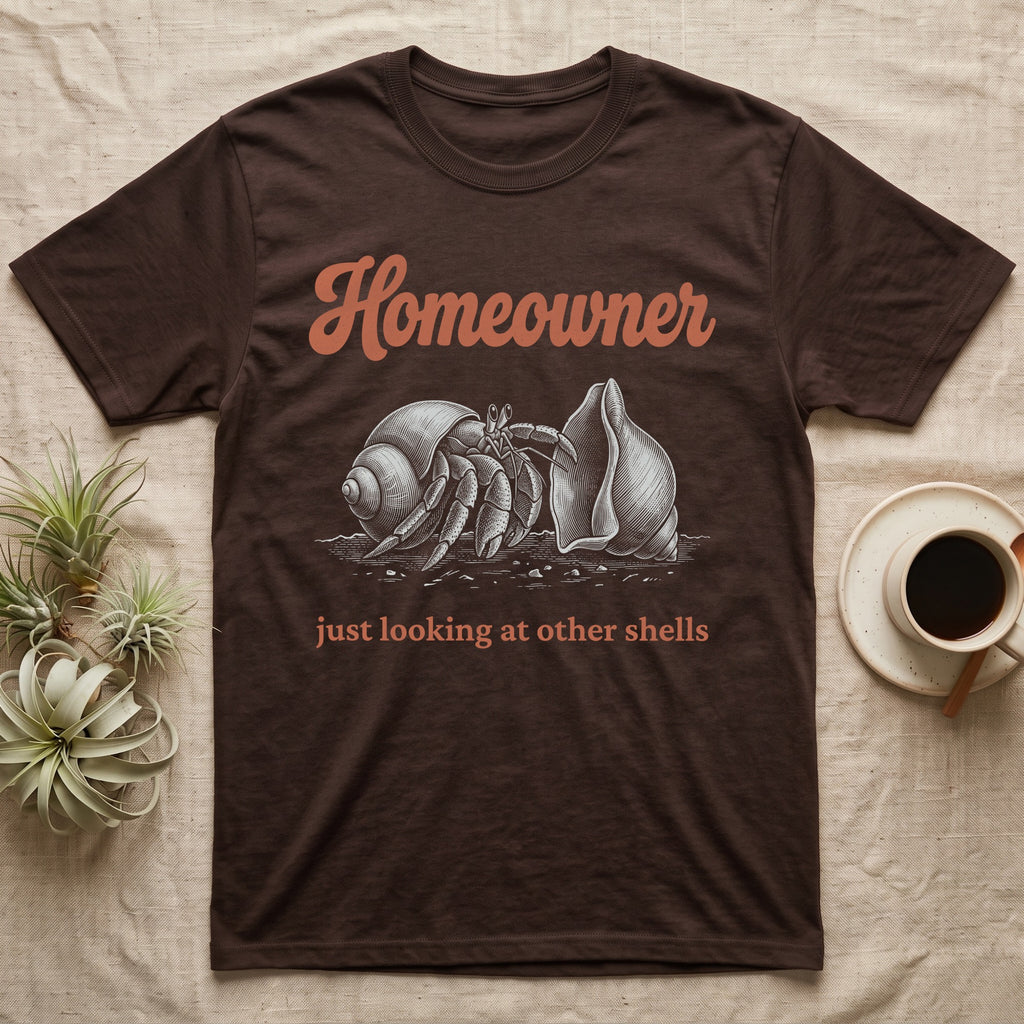 Hermit Crab Homeowner T-Shirt in Dark Chocolate — White-line engraving of a land hermit crab eyeing a bigger empty shell, under orange script Homeowner and a serif line
